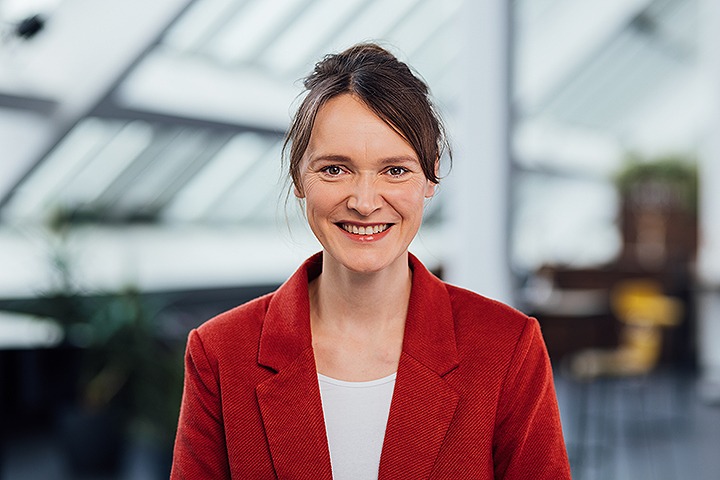 Profilbild Stephanie Engler mit rotem Blazer und zusammengebundenen Haaren und breitem Lächeln